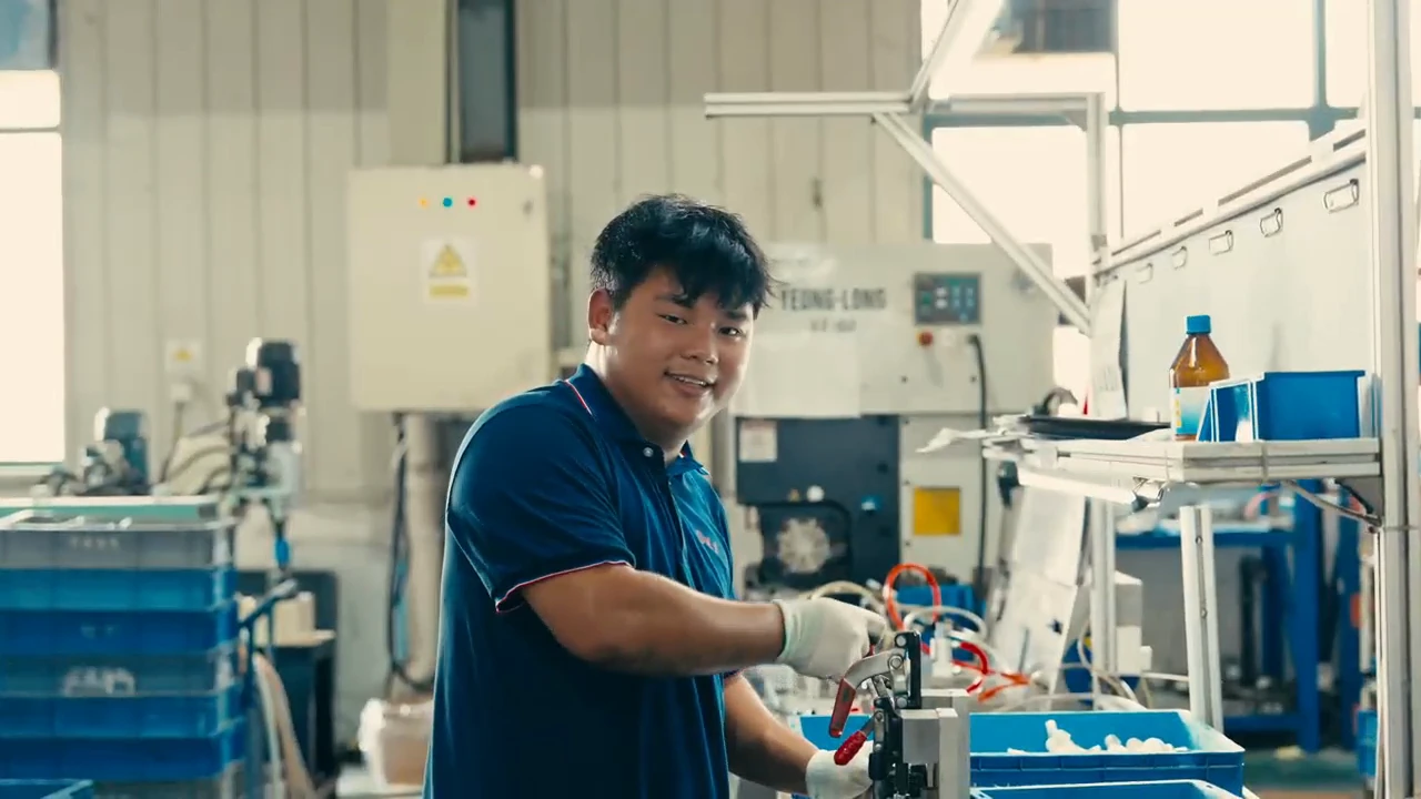 工厂宣传片中穿蓝色工作服的员工在设备旁微笑